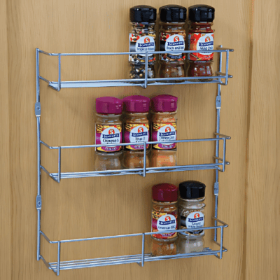 3-tier spice rack mounted on wooden cupboard door holding assorted spice jars