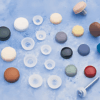 Assorted coloured silicone end caps with screws on a textured blue surface, used for sealing and protecting fittings and threads