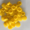 Pile of bright yellow silicone end caps used as protective rubber plug covers for pipes, tubes, and fittings