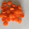 Pile of bright orange silicone end caps or rubber plug covers used for sealing tubes, fittings, or pipe ends