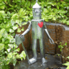 Tin Man statue with red heart holding axe in garden corner